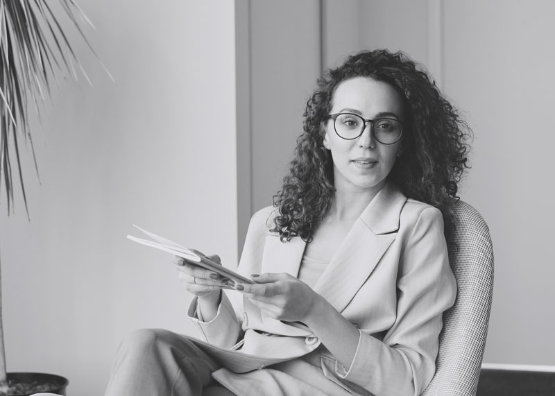 Photo of Irena Porter sitting in a chair holding a notepad